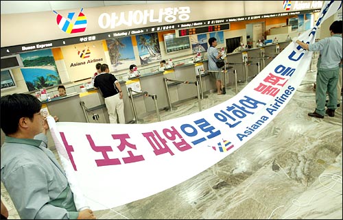 지난 18일 서울 김포공항 아시아나항공 탑승수속 창구에 직원들이 '시민들에게 불편을 드려 죄송하다'는 현수막을 붙이고 있다. 